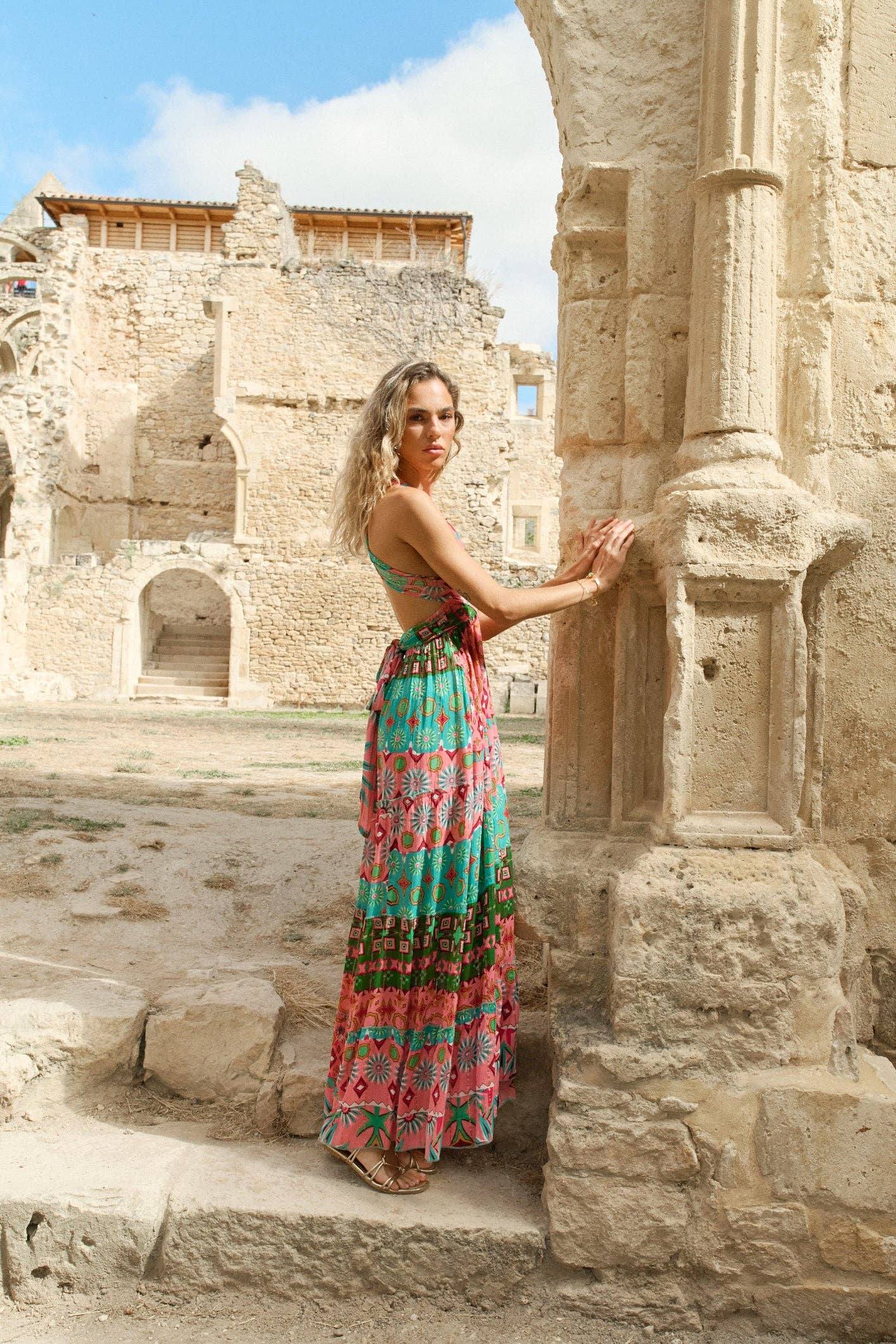 Frau im Goa Pink Kleid mit Wickeldesign vor alten Steinmauern