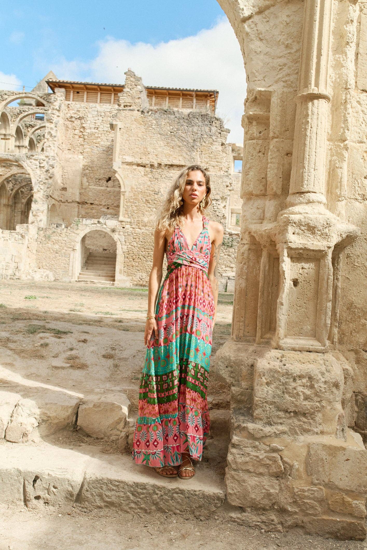 Frau läuft durch antike Ruinen im Goa Pink Maxikleid mit buntem Boho-Print