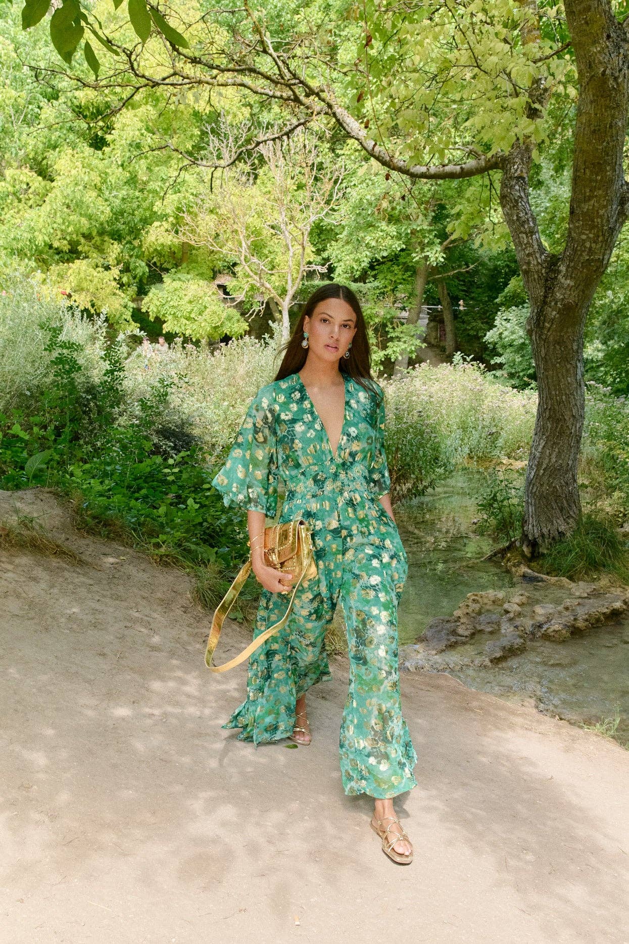 Model kombiniert Jumpsuit „Kenia“ mit goldener Tasche und Ohrringen im Boho-Stil