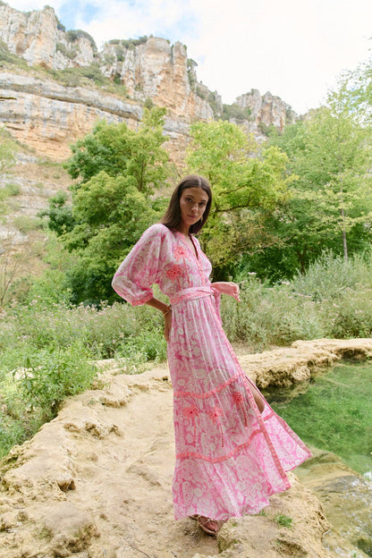 Model in Seitenansicht des Sahara Rose Maxikleids mit fließendem Rockteil