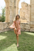 Model läuft in sommerlicher Kulisse im kurzen Viskosekleid mit rot-braunem Muster.