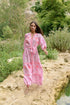 Model trägt Sahara Rose Maxikleid in floraler Landschaft – Vorderansicht in Bewegung