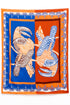 Produktfoto: flach gelegter Pareo mit Papageien auf Blau-Orange-Hintergrund.