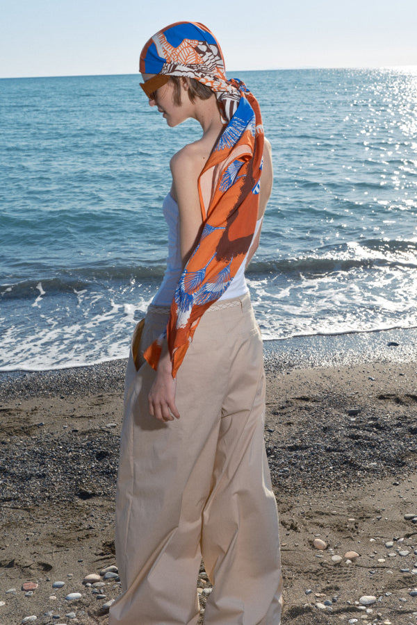 Frau trägt den Pareo Blau-Orange als Tuch am Meer.