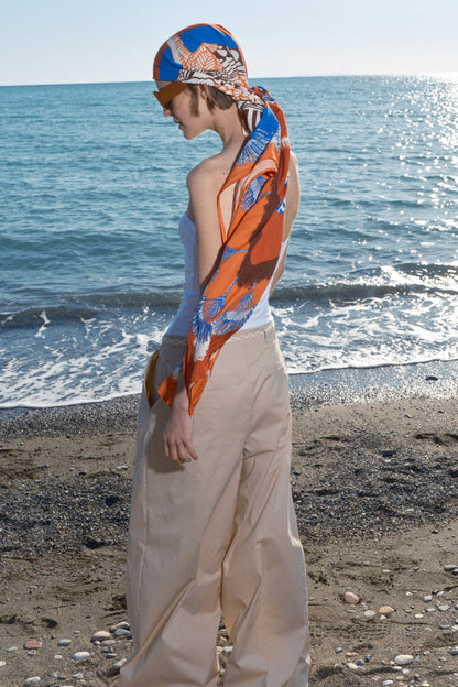 Frau trägt den Pareo Blau-Orange als Tuch am Meer.